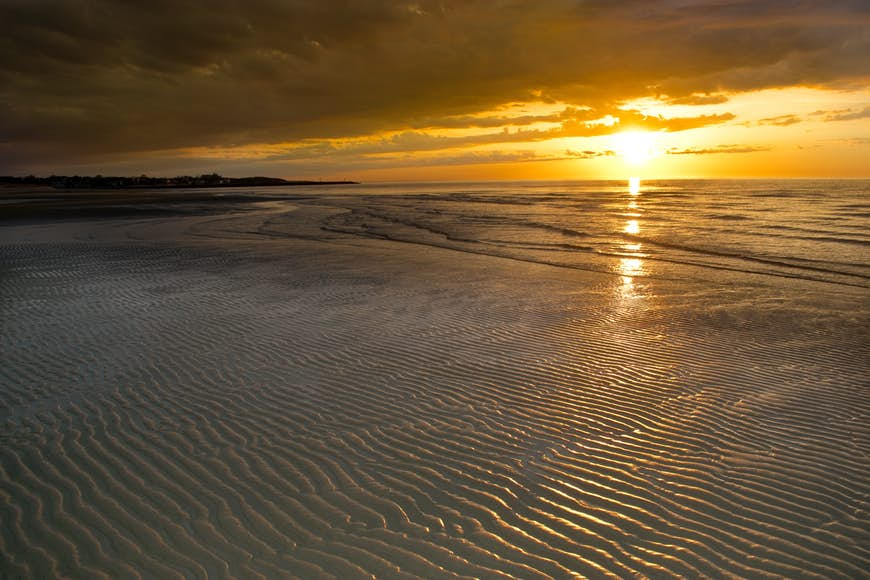 Rays from a setting sun highlight ripples on the shore of a beach in Provincetown, Mass.