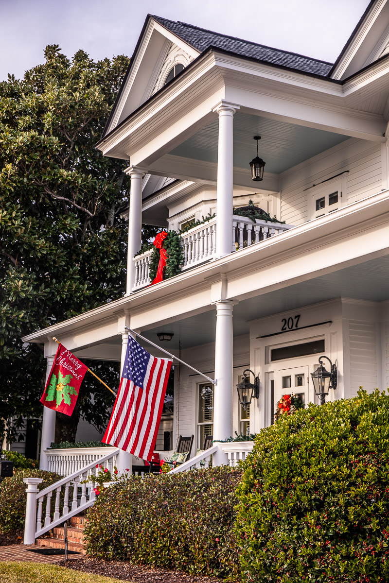 white historic home with flags out the front