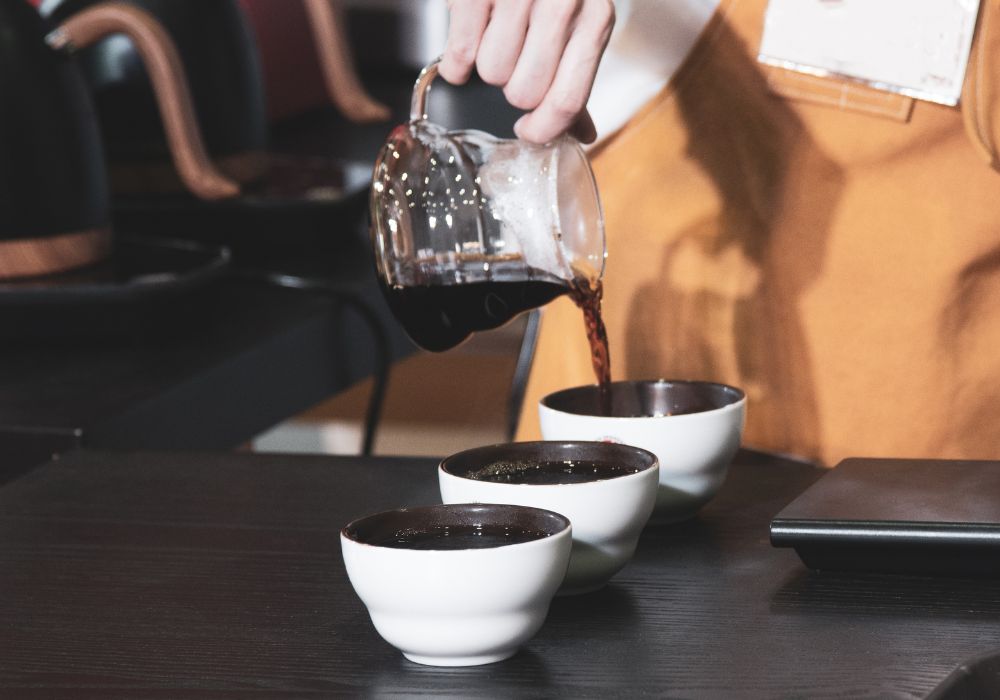 A barista pouring coffee on a counter.