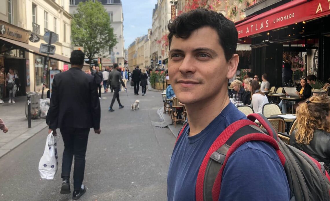 Nomadic Matt walking down a busy and anrrow street in Paris, France