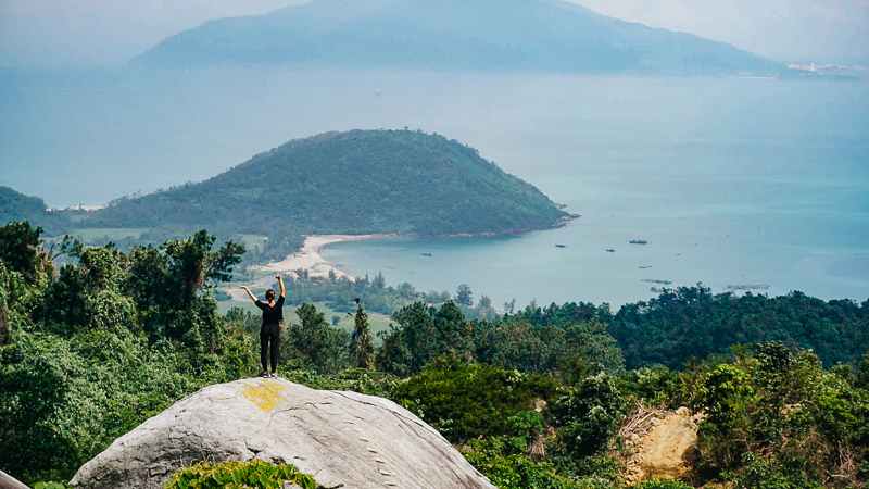 lady standing on giant boulder with dramatic views over the coastline