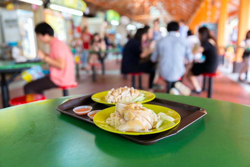 A dish of chicken and rice on a table in a hawker food center, Singapore