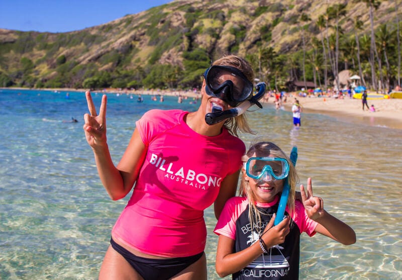 woman and girl at Hanauma Bay Oahu wearing snorkels and giving peace signs to the camera