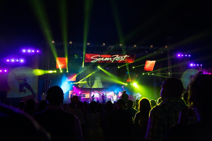 A nighttime music festival with bright neon lights shooting out from the stage