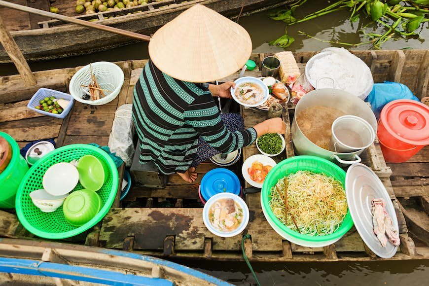 Vietnamese Pho seller on floating market - woman selling noodle soup from her boat in the Mekong river delta, Vietnam.