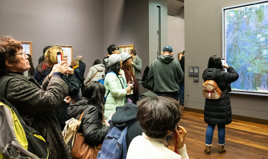 Visitors admire and take photos of “Blue Water Lilies” by Impressionist Claude Monet in the Musee d’Orsay, Paris, France