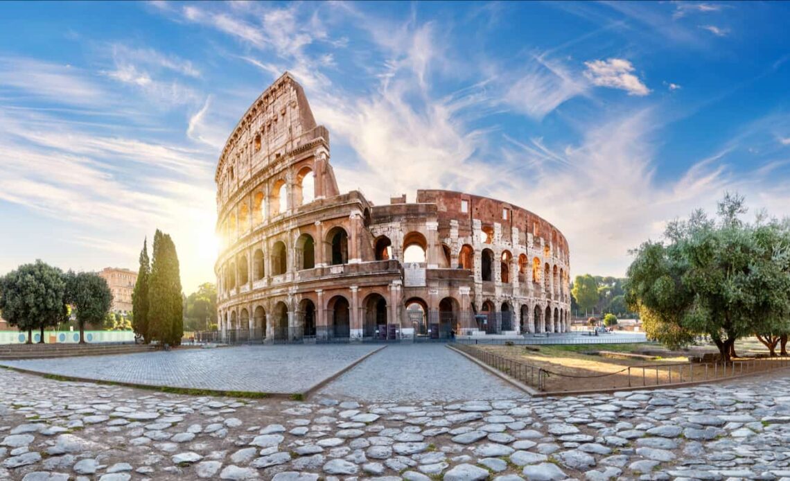 The massive colosseum in Rome, Italy with the bright sun in the background on a sunny day