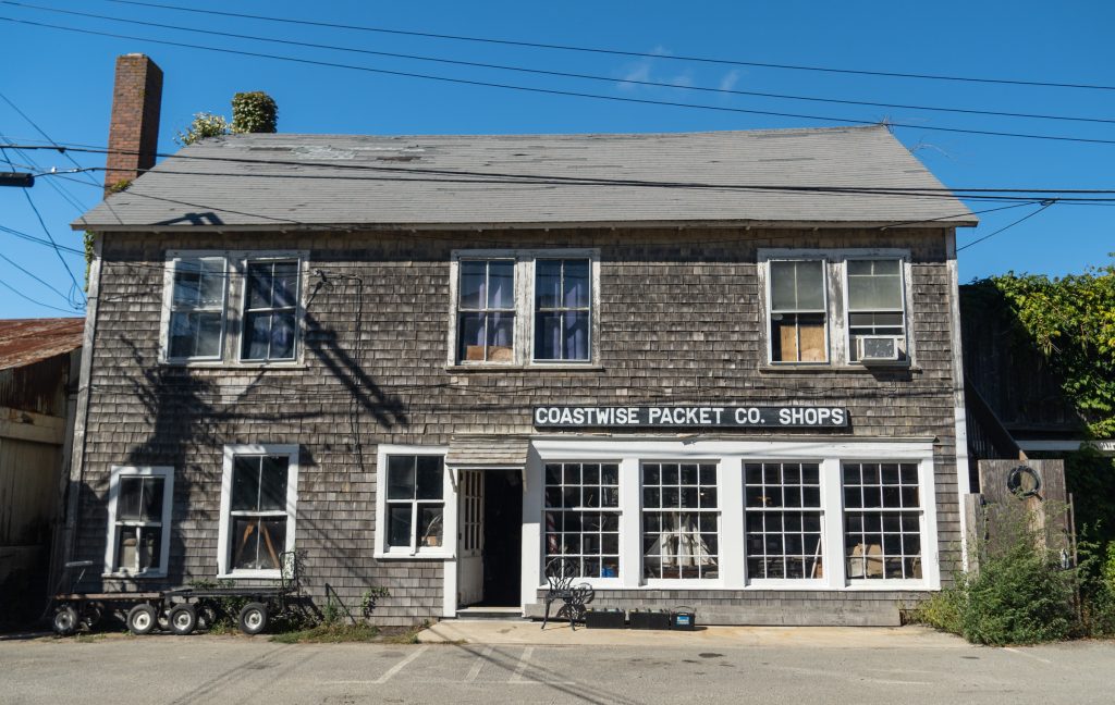 A shingled house with a sign reading "Coastwise Packet Co Shops"