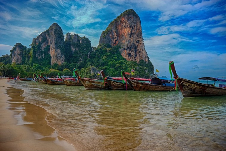 Beach in Thailand and traditional boats creating the most romantic atmosphere for a long walk.