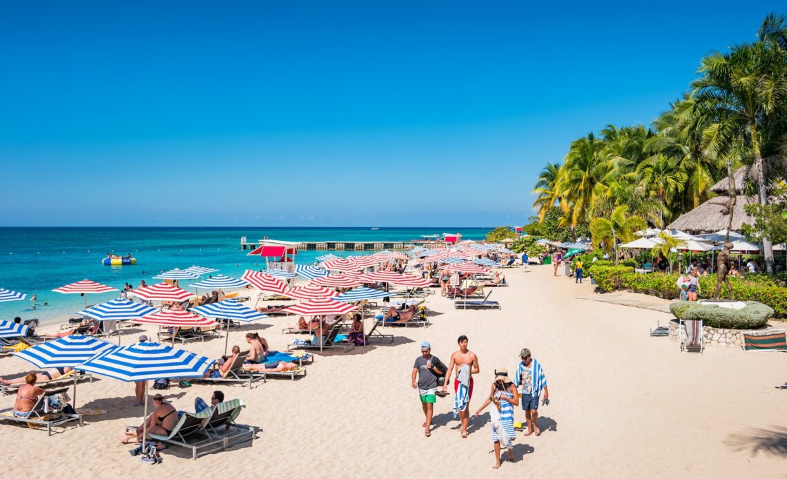 People enjoy Doctor's Cave Beach, a famous, white, sandy beach in Montego Bay Jamaica on a sunny day.