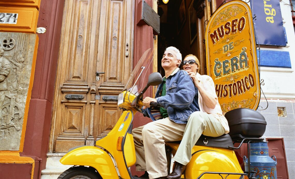 A couple sit on a scooter together outside the wax museum in Buenos Aires