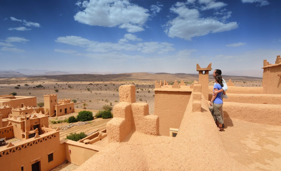 Young couple in a kasbah looking out at a view of a sand-colored city