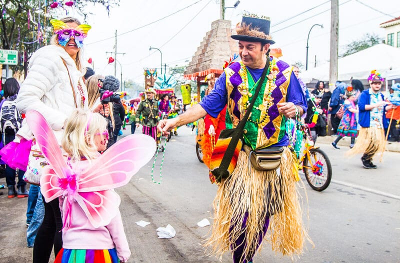 man in costume handing beads to woman and girl dressed in fairy costumes 