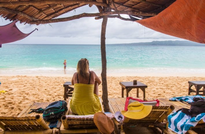 woman sitting under shade on Puka Beach looking at water