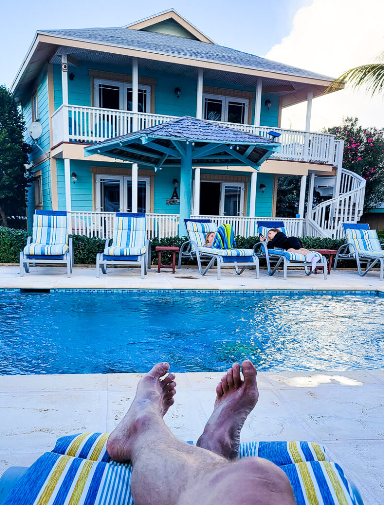 Man's feet on a sun bed in front of a pool