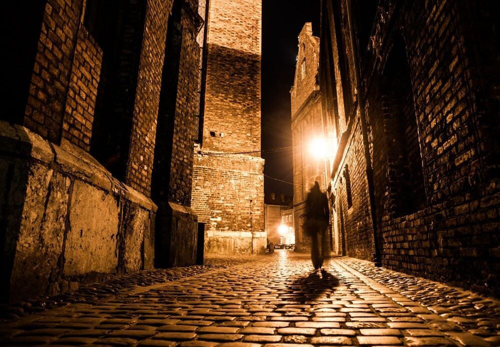 Illuminated cobbled street with light reflections on cobblestones  in old historical city by night.