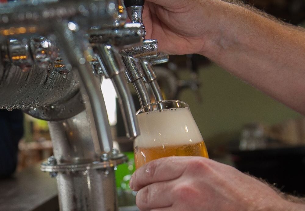 A man uses the draft beer taps during a brewery tour.