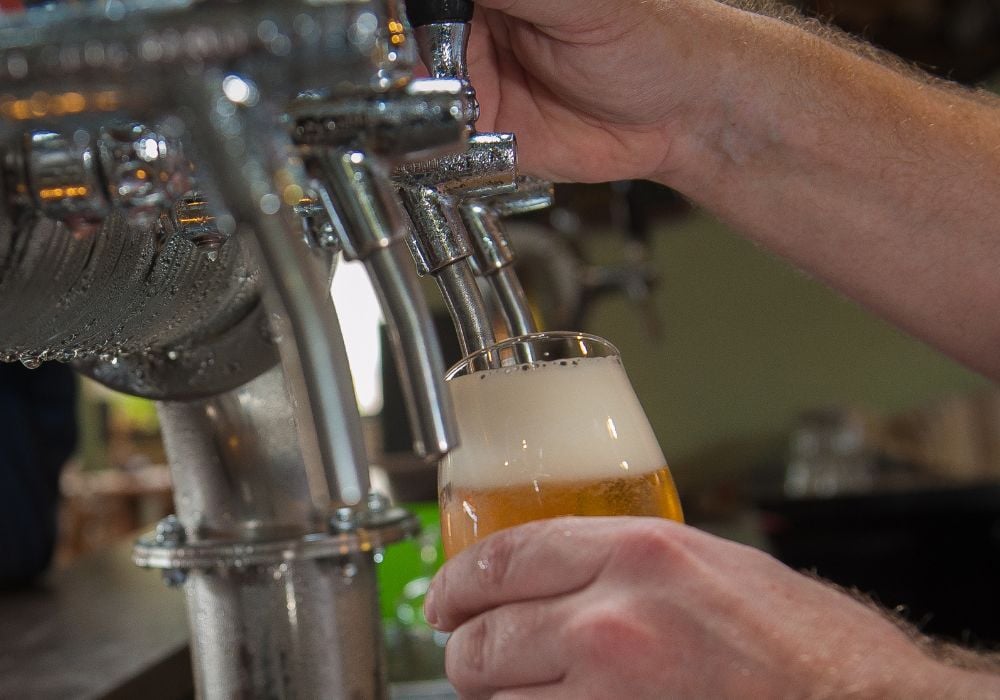 A man uses the draft beer taps during a brewery tour.