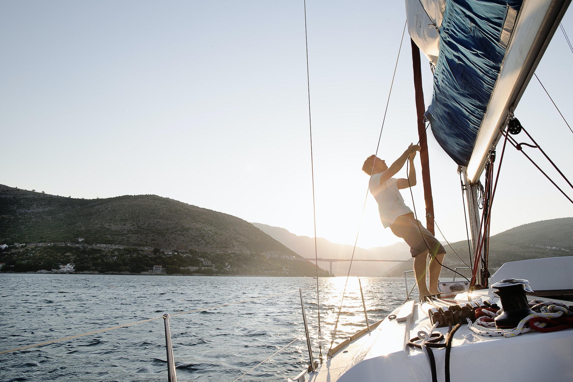 Man hoisting sail, backlit