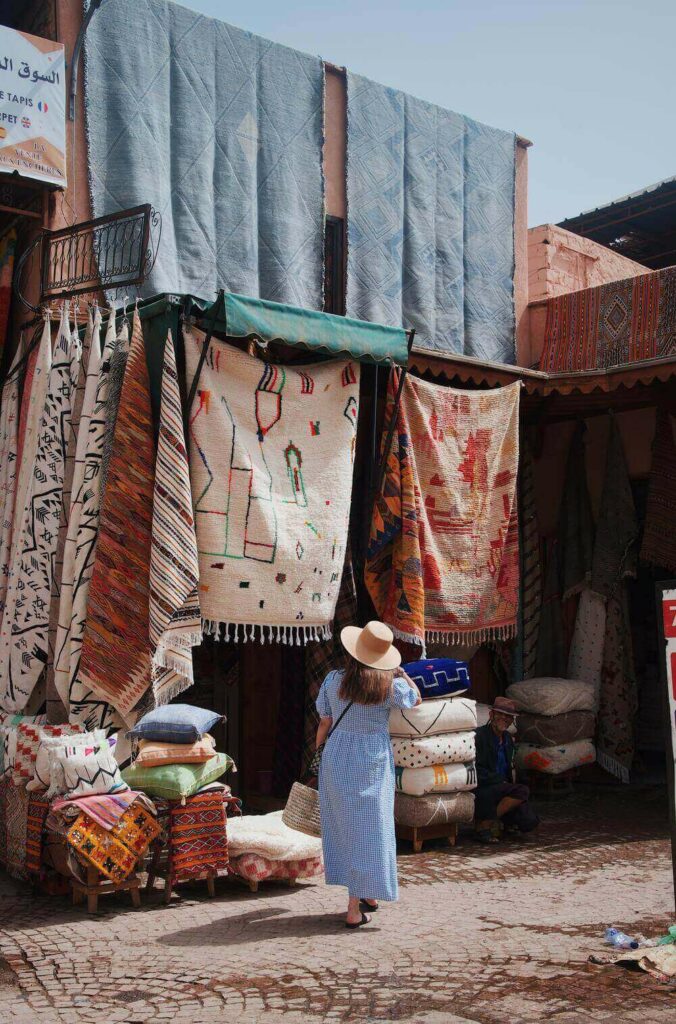 woman walking past a carpet stall in the souk markets