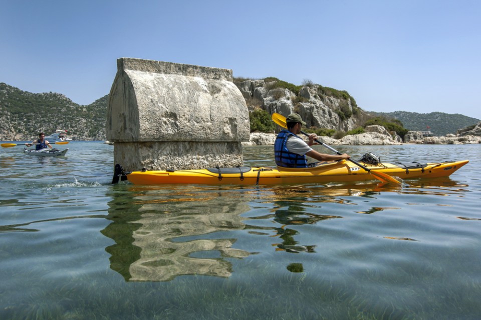 A kayaker paddles past one of the sunken Lycian stone tombs at the ancient city of Simena. The area, which is today known as Kalekoy, is situated on the Mediterranean Sea of Turkey.