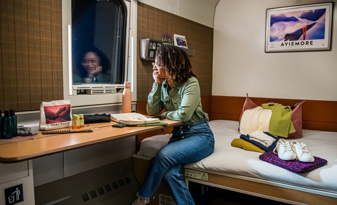 A woman looks out the window in a Caledonian Double room aboard the Caledonian Sleeper overnight train between London and Scotland