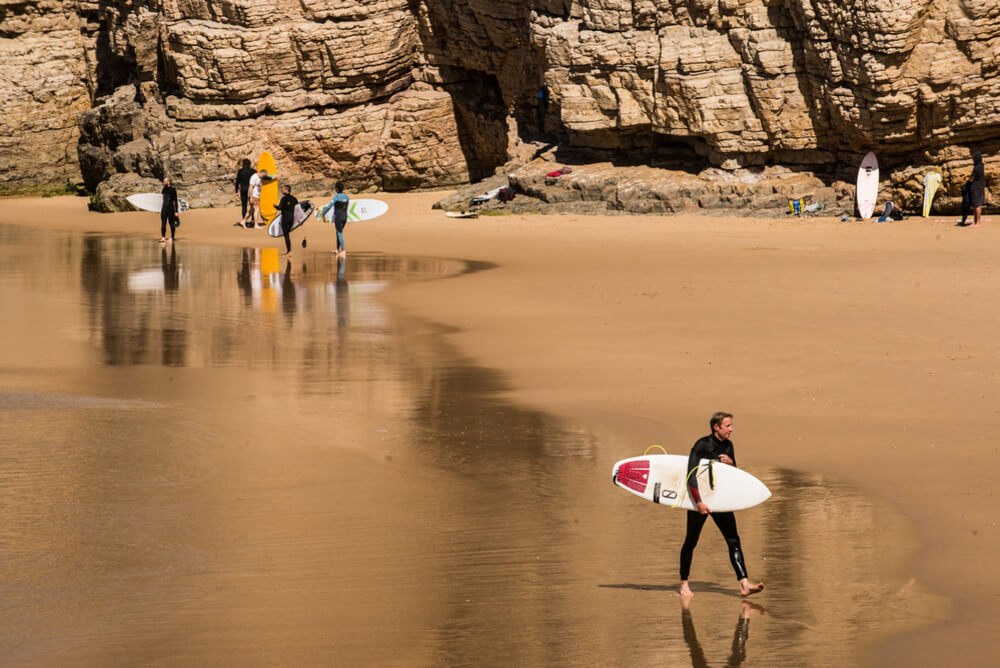 people walking on beach with surfboards