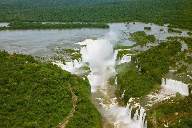aerial view of river spilling into iguazu falls surrounded by lush greenery