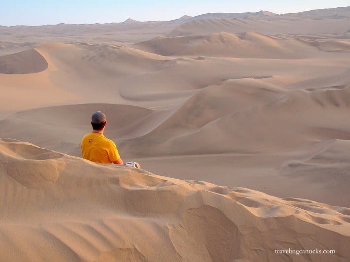 man sitting on the sand dunes at Big Sandbox Huacachina Peru