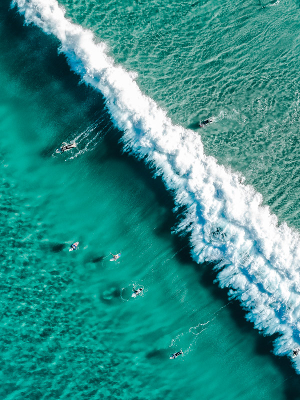 Aerial overlooking surfers catching waves at Tamarama Beach, 