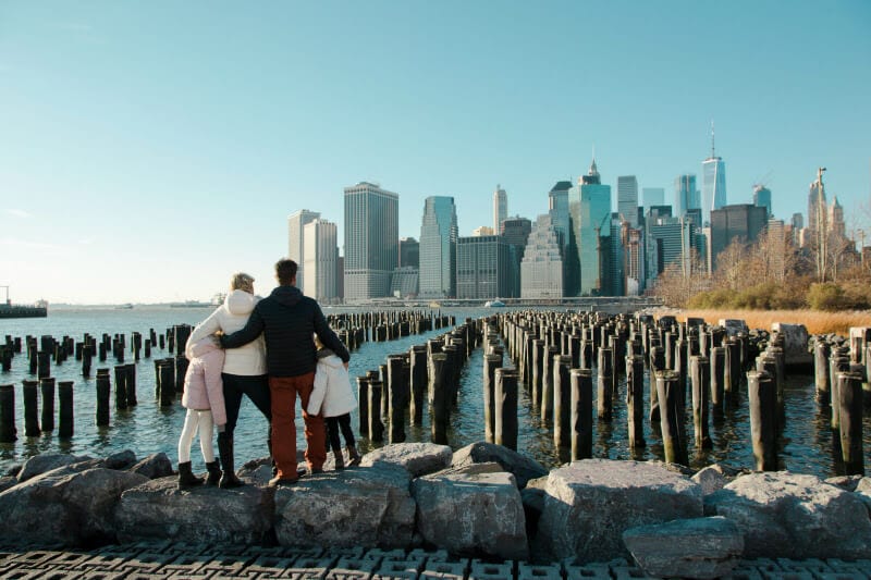 people standing on rocks looking out at a city skyline