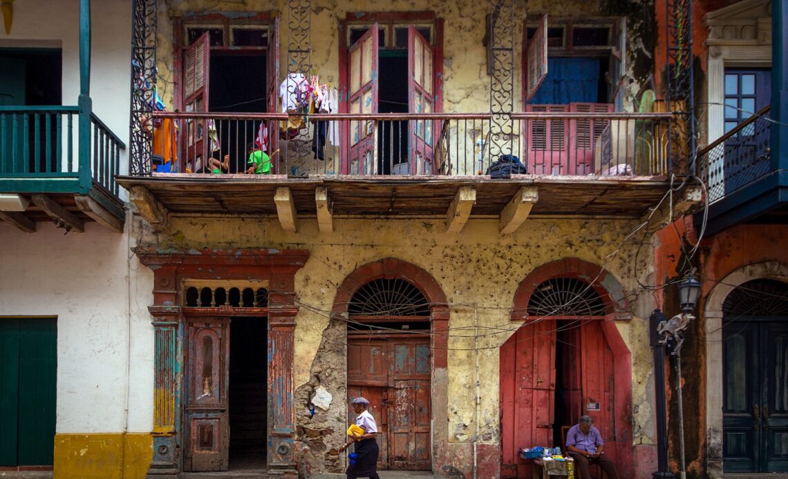 Woman walking the streets and a vendor sleeping, in historic Casco Viejo district of Panama City, Panama.