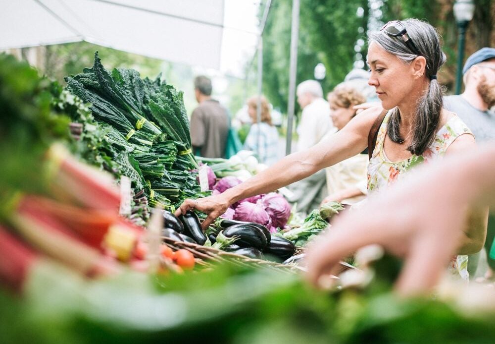 A woman shopping in a local farmer's market with fresh and organic vegetables.