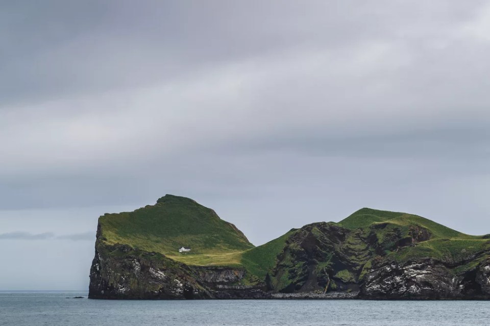 Lonely house on Ellidaey island in Vestmannaeyjar archipelago, Iceland. Rocky and green island. Nordic landscape.