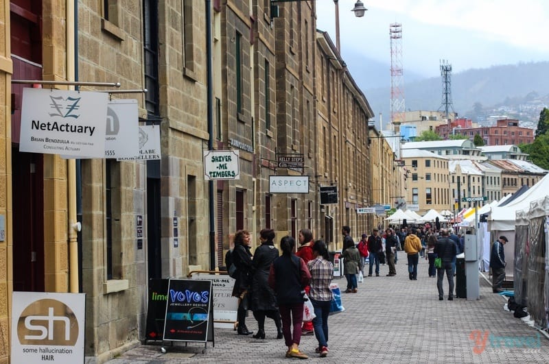 people waking around Salamanca Place, nest to old sandstone buildings