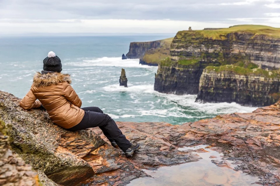 Young tourist woman admire the view at Cliffs of Moher