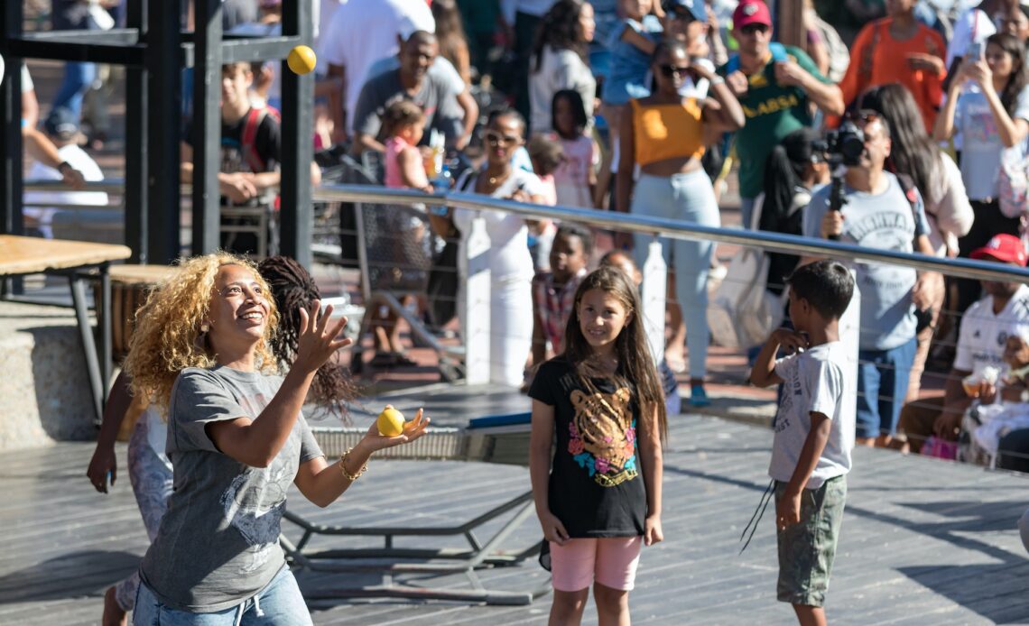 Crowds of people look on at an entertaining juggling balls