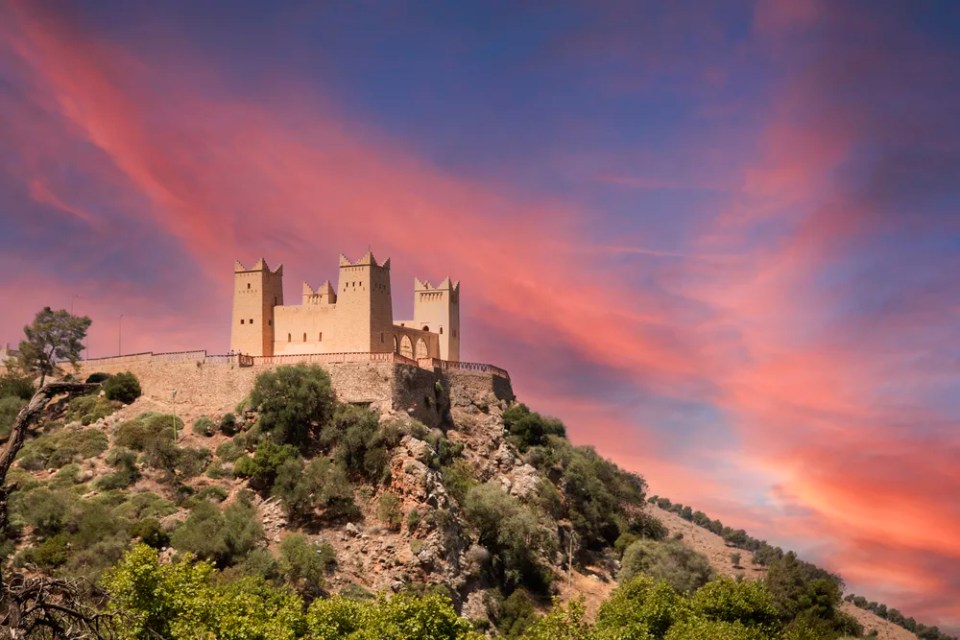 Imposing Kasbah of Beni Mellal which is a Berber castle and historical monument in the city of Beni Mellal, Morocco with a beautiful reddish and orange sky. This fortress is in the Tadla plain.