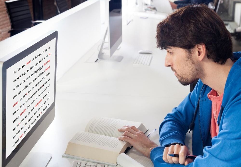 A young man is proofreading and editing on his computer.