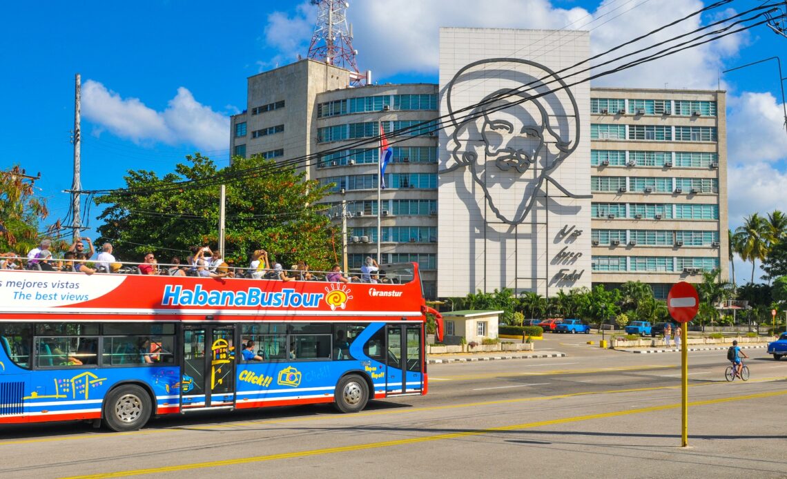 Blue and red tourist sightseeing on a bus tour at Plaza de la Revolucion (Revolution Square) in Havana.