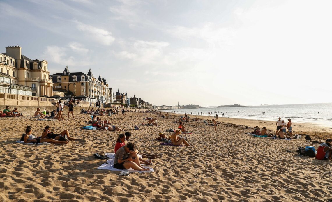 Tourists sunbathe on a beach by the sea in St-Malo, Brittany, France