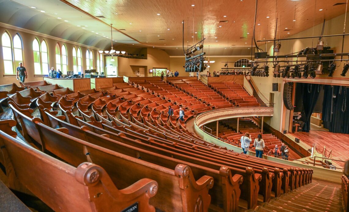 Interior of legendary Ryman Auditorium, seen from the back of the balcony looking out over rows of wooden seats and the stage