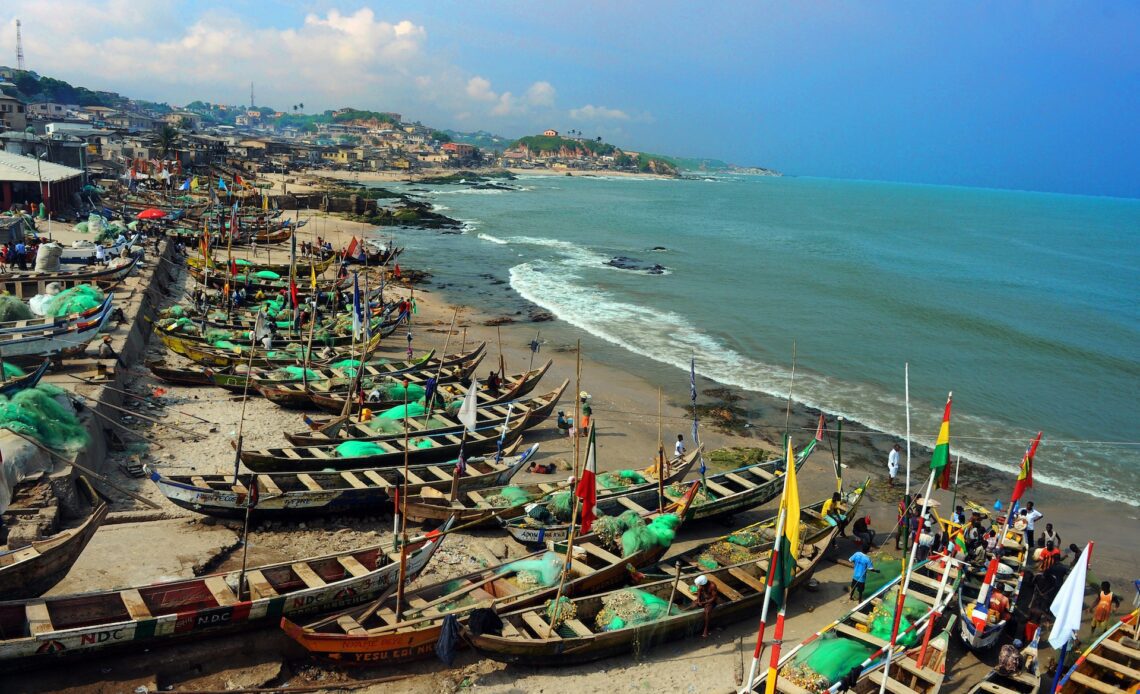 Wooden fishing boats with colorful flags dominate a sandy beach