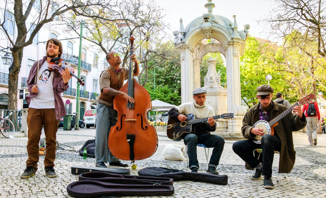 Four musicians play folk music in a public square in Lisbon