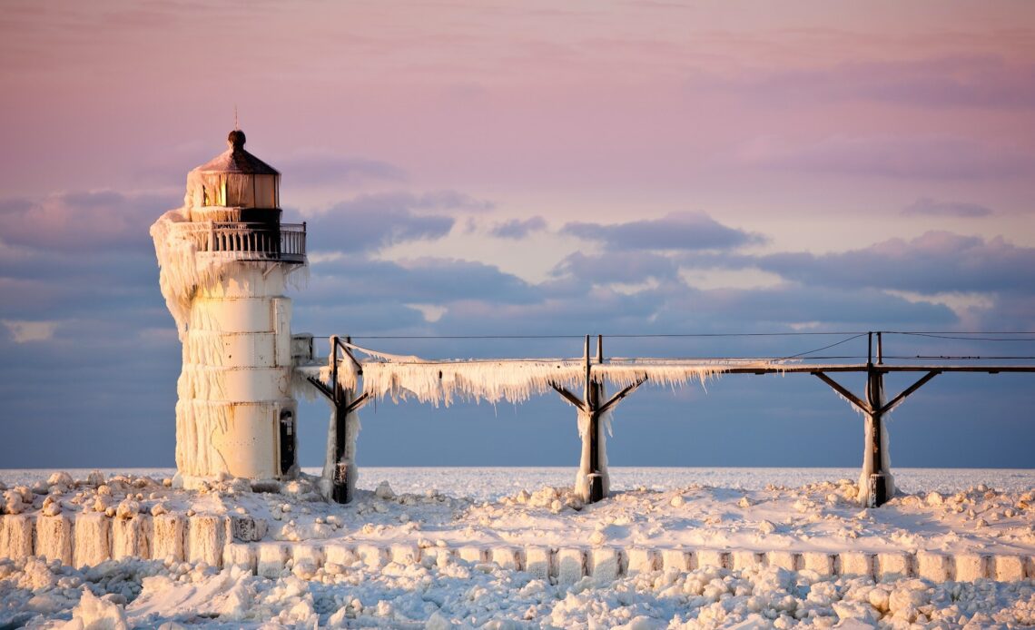 Ice and snow engulf a lighthouse on the edge of a lake