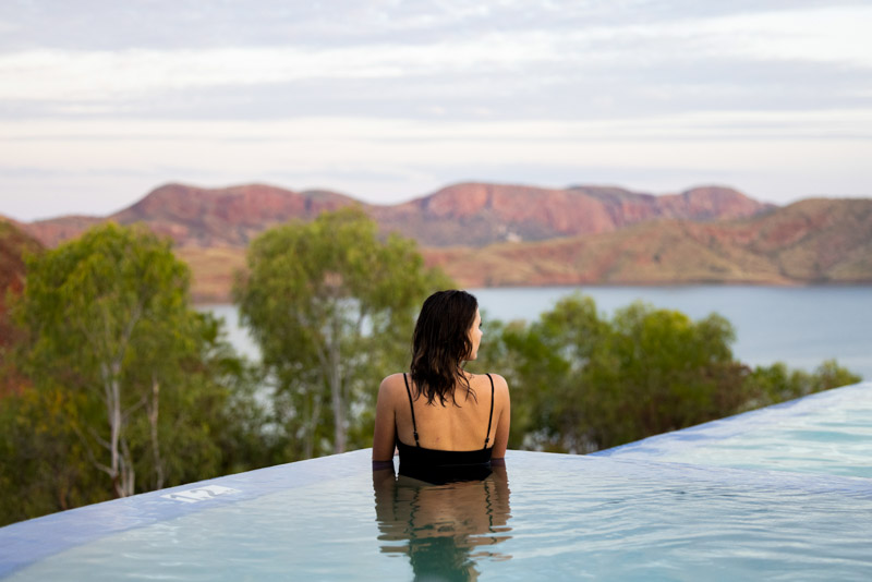 Swimmer at infinity pool looking at view of Lake Argyle, East Kimberley