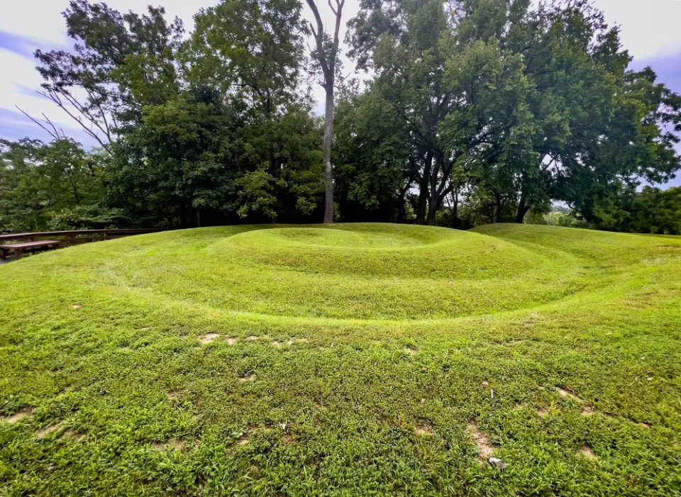 Side view closeup of the coiled tail of the snake at Serpent Mound in Ohio, the largest effigy mound in the world. Ridges of the prehistoric Native American engineering earthwork art are clearly visible covered in green grass.