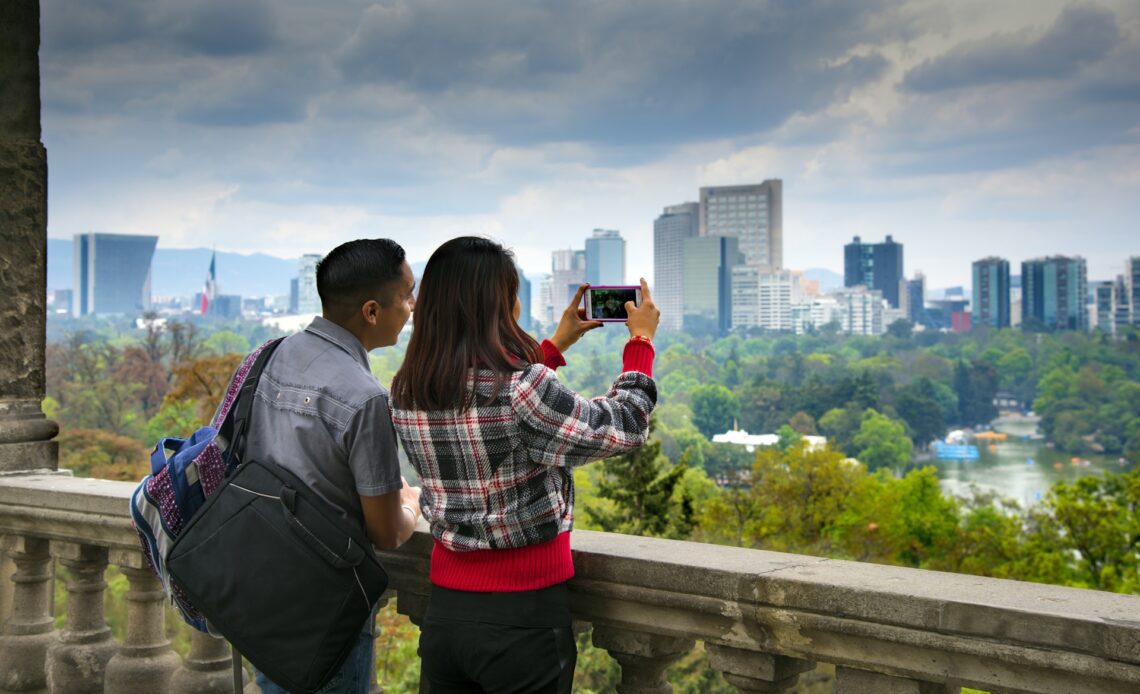 Visitors to Chapultepec Park seen from behind, taking photographs of the views of Mexico City