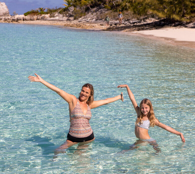 Mother and daughter standing in waist deep water at a beautiful beach in The Bahamas