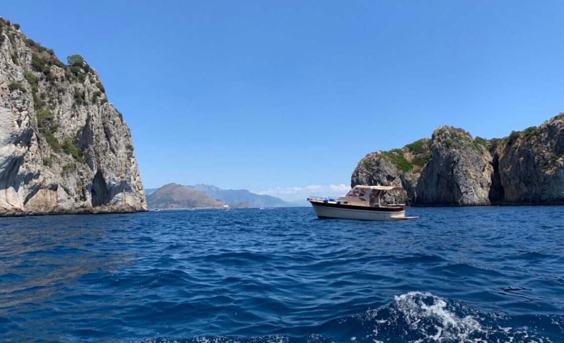 A boat on the water off the coast of Capri, Italy with the Amalfi Coast in the background